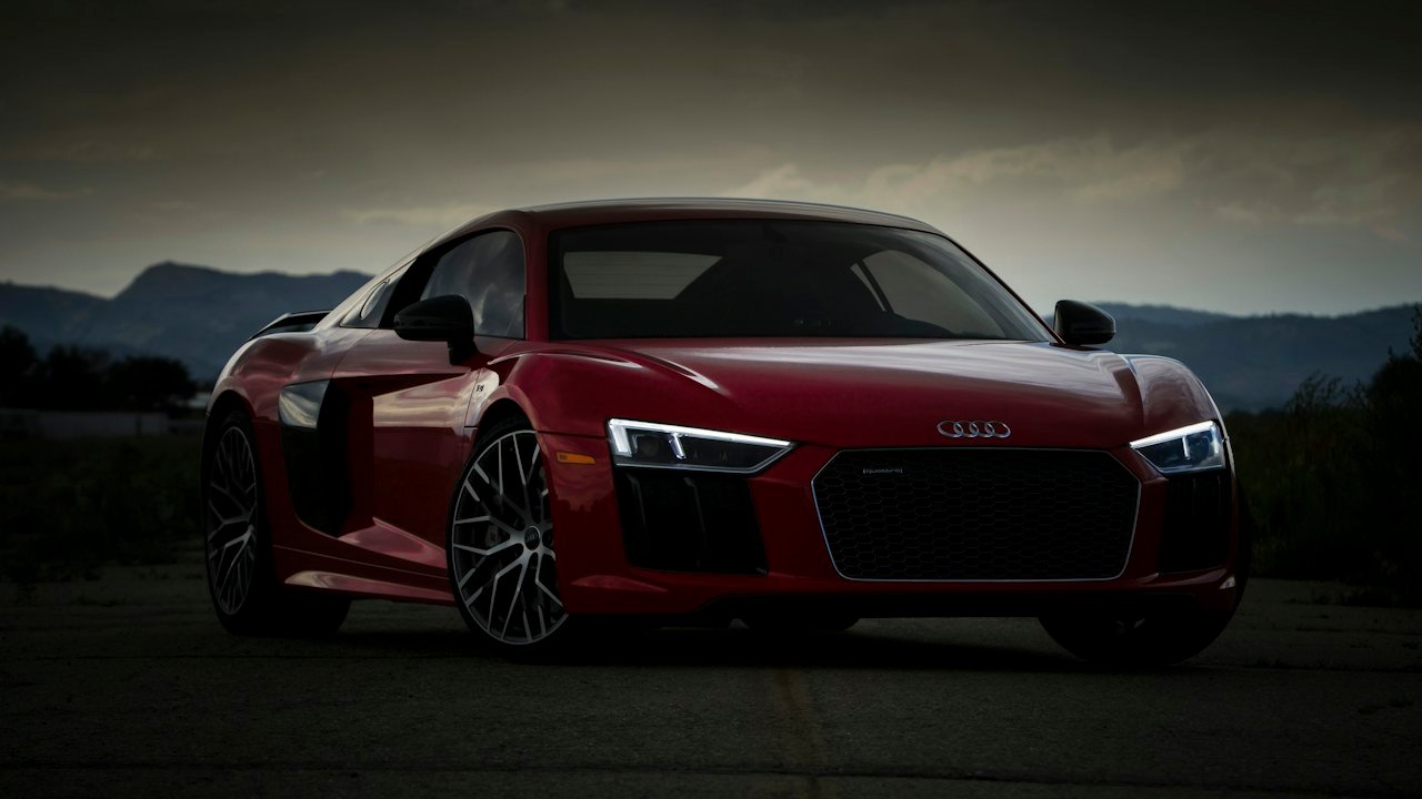 Red sports car with its headlights on at dusk